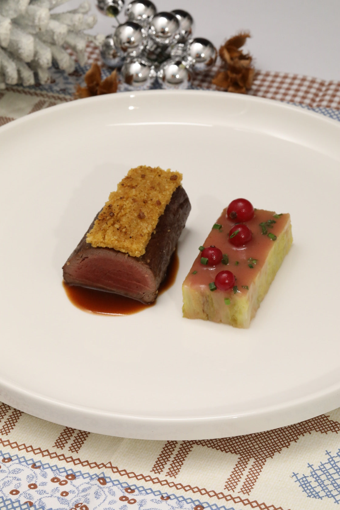 Rehrücken mit Bucheckernkruste, getrüffelter Wirsingterrine, Preiselbeeren und geräucherter Bucheckern-Wildjus